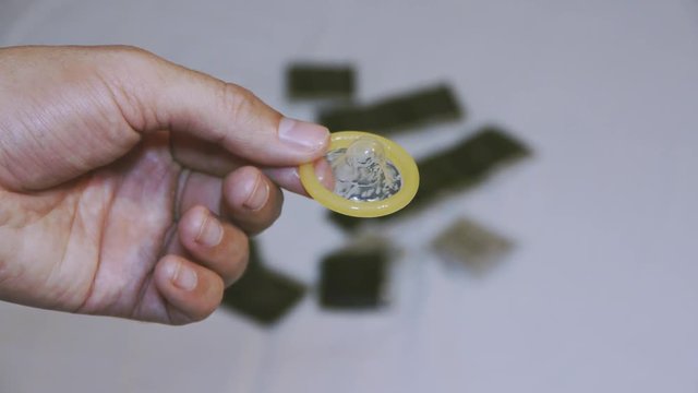 Ready to use condom in the man's hand. Male contraceptive outside the package. Health. AIDS