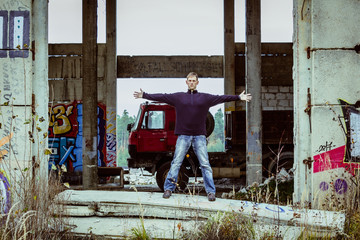 Portrait of young man stand in abandoned building with truck, street art photo