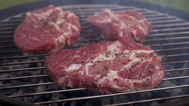Cooking juicy raw meat steaks on the bbq grill