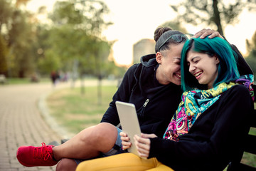 Two young girls sitting in the park, having fun, taking photos and enjoying time spent together. Couple concept.