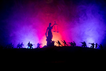 War - no justice concept. Military silhouettes fighting scene and The Statue of Justice on a dark toned foggy background.