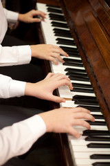 Fototapeta premium Children play piano in four hands