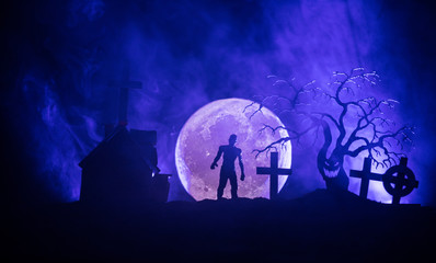 Scary view of zombies at cemetery dead tree, moon, church and spooky cloudy sky with fog, Horror...