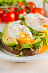 Avocado toast, cherry tomato and poached eggs on wooden background. Breakfast with vegetarian food, healthy diet concept.
