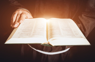 Obraz premium A monk in robes with holy bible in their hands praying in the church