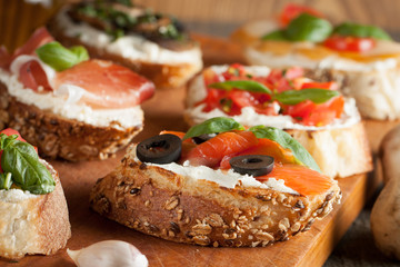 Italian tomato and cheese bruschetta. Tapas, antipasti with chopped vegetables, herbs and oil on grilled ciabatta and baguette bread.