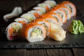 Maki rolls and nigiri sushi on a wooden table. Salmon, avocado and caviar rolls.