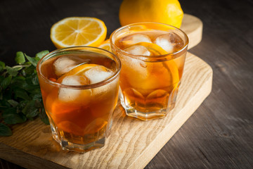 Glasses of cold ice tea with lemon, ice, mint on background. Homemade lemonade. Spring and summer drinks and beverages concept. 