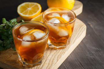 Glasses of cold ice tea with lemon, ice, mint on background. Homemade lemonade. Spring and summer drinks and beverages concept. 