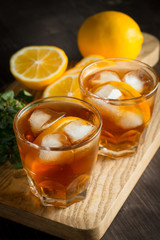 Glasses of cold ice tea with lemon, ice, mint on background. Homemade lemonade. Spring and summer drinks and beverages concept. 