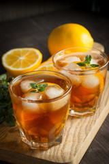 Glasses of cold ice tea with lemon, ice, mint on background. Homemade lemonade. Spring and summer drinks and beverages concept. 