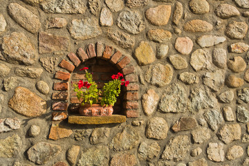 Flower pot with red flowers, detail from old hose stone wall at Kalambaka, Thessaly, Greece