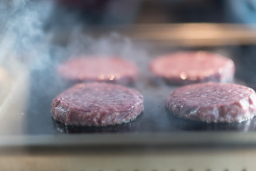 Fresh meat cutlets in a frying pan grill. A lot of steam or smoke