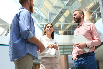 Group of young modern people in smart casual wear standing in creative office.