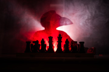 Man playing chess. Scary blurred silhouette of a person at the chessboard with chess figures. Dark toned foggy background.