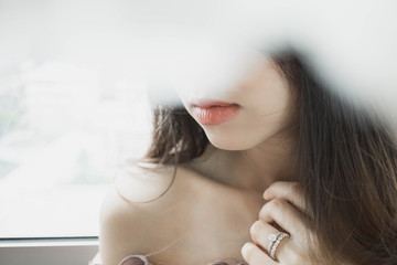 Close up of elegant diamond ring on woman finger with window and sunlight tone background.Love and...
