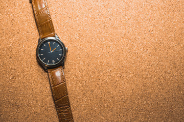 Top view of a brown hand watch over a brown surface