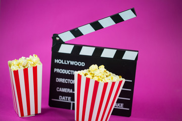 Film flap with popcorn on a pink background - obrazy, fototapety, plakaty