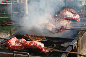 Appetizing delicious fried pieces of meat on skewers are roasted on a large grill in the open air. The chef prepares a barbecue.
