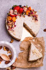 White cake with fruit, berries and almonds on a light background. Piece of cake.