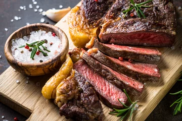 Rolgordijnen Grilled beef steak ribeye on wooden cutting board.  © nadianb