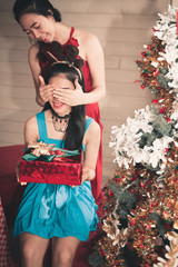 Portrait of Asian Woman Surprised and Covering Eyes of Her Friend Before Open Christmas Gift, Pretty Young Women Getting Present From Her Friend in Holiday Christmas, Birthday Party. Celebration Event