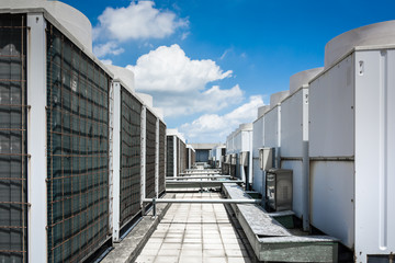Air compressor machine part of air conditioner system on roof deck with sky background.