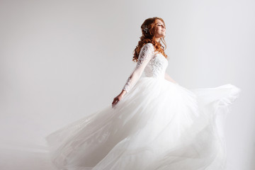 Lovely young woman bride in a lavish wedding dress. Light background.