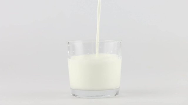 Pouring milk into glass on white background