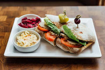 Grilled chicken sandwich made with homemade bread, tomato and lettuce served with beetroot salad and coleslaw.