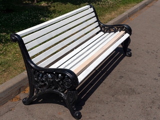 White wooden bench in the park on the street.
