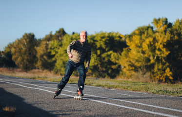 The old man goes on rollers in the autumn park. Happy pension. Active old people.