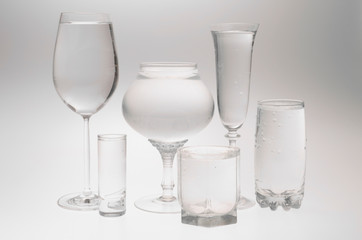 Transparent still life with glasses of different heights filled with water on a white background. Mock-up.