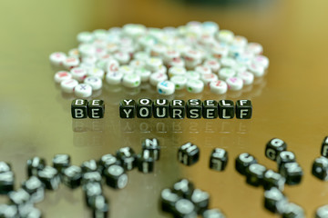 BE  YOURSELF  written with Acrylic Black cube with white Alphabet Beads on the Glass Background