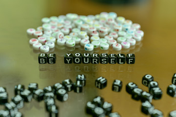 BE  YOURSELF  written with Acrylic Black cube with white Alphabet Beads on the Glass Background
