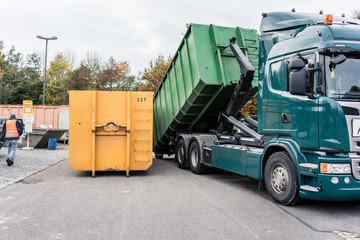 Truck loading container with waste in recycling center to transport