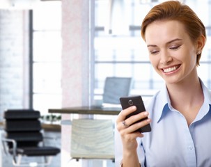 Obraz premium Young businesswoman using mobilephone at office
