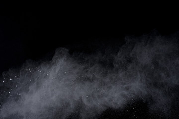 White powder explosion on black background. Dust splatted isolated. Paint Holi.
