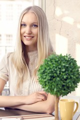 Portrait of attractive blonde girl sitting at home