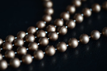 Long necklace of brown beads on a dark background close up