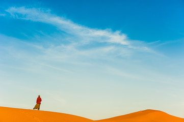 Fototapeta na wymiar Girl walk in Erg Chebbi Desert, Sahara Desert near Merzouga, Morocco