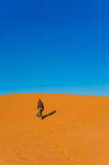 Fototapeta na wymiar Girl walk in Erg Chebbi Desert, Sahara Desert near Merzouga, Morocco