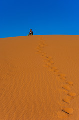 Fototapeta na wymiar Girl sitting in Erg Chebbi Desert, Sahara Desert near Merzouga, Morocco