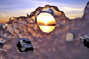 View of winter sunset through holes in ice