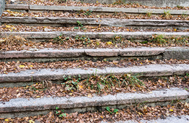 Old stairs in very bad condition with autumn leaves near an abandoned factory in Romania.