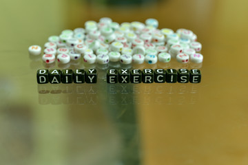 DAILY EXERCISE  written with Acrylic Black cube with white Alphabet Beads on the Glass Background