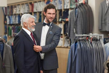 Attractive helping customer trying on jacket in show room.