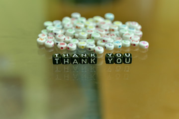 THANK YOU  written with Acrylic Black cube with white Alphabet Beads on the Glass Background