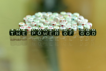 THE POWER OF GOD written with Acrylic Black cube with white Alphabet Beads on the Glass Background