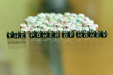 THE POWER OF MONEY written with Acrylic Black cube with white Alphabet Beads on the Glass Background